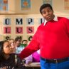 As Doris (Kyla Pratt) looks on in embarrassment, Fat Albert (Kenan Thompson) explains to her class why she needs his help.